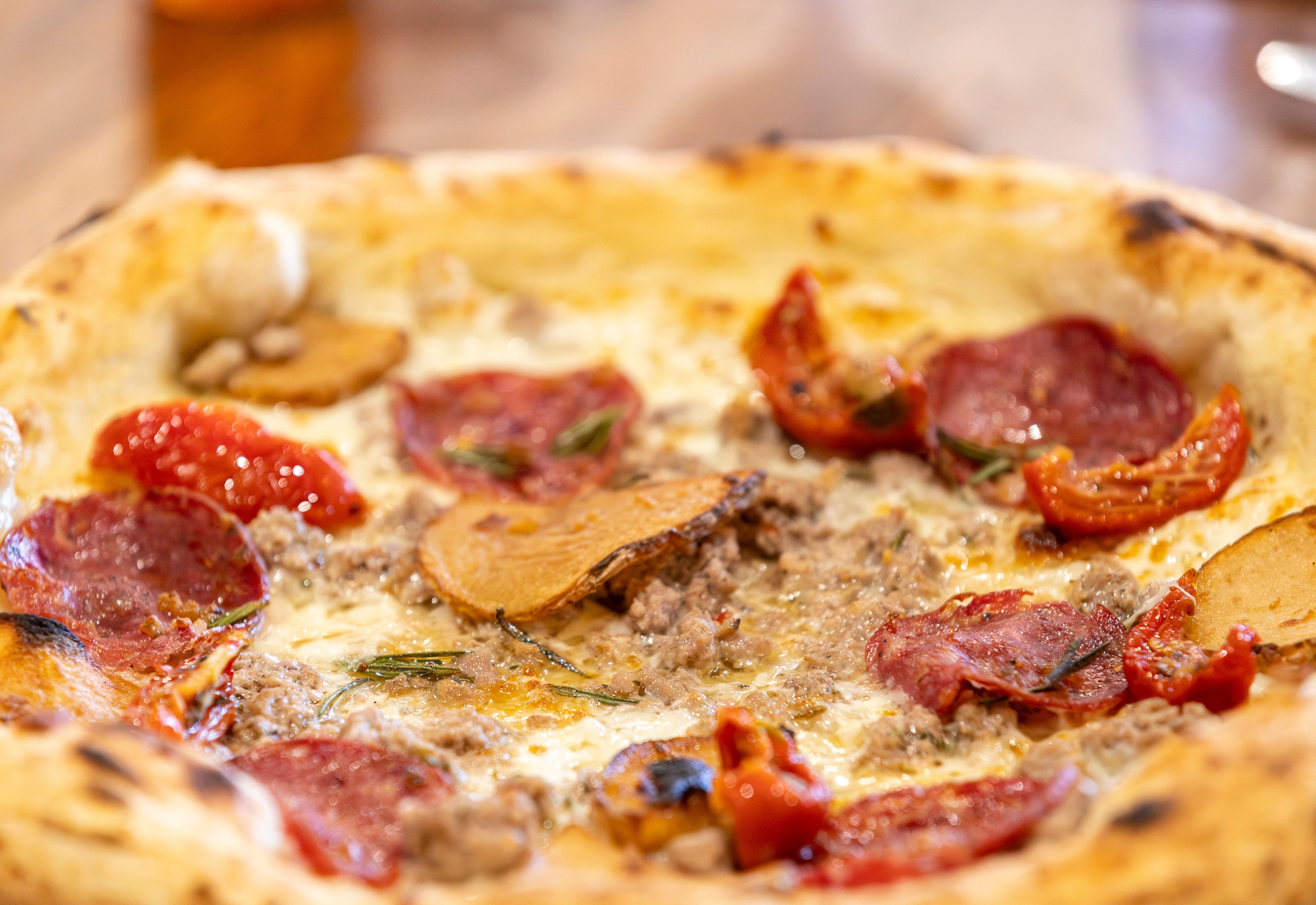 Wood-fired pizza with salami, roasted pumpkin and cherry tomatoes at Bianco Italian in Caloundra