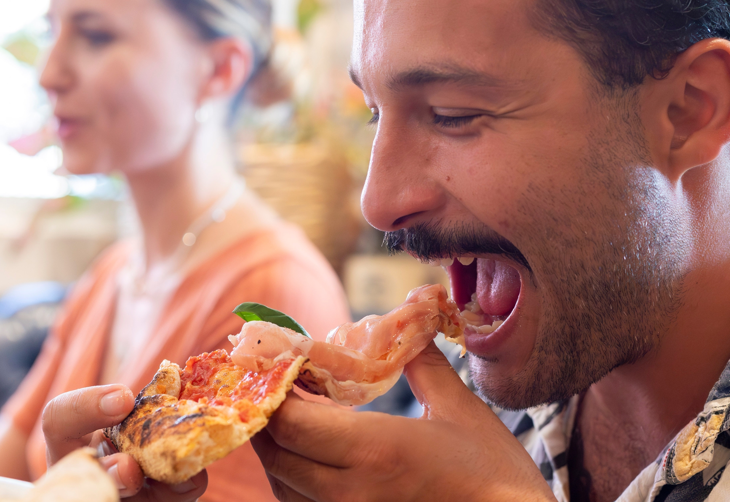 Man eating a slice of prosciutto pizza at Bianco Italian restaurant in Caloundra