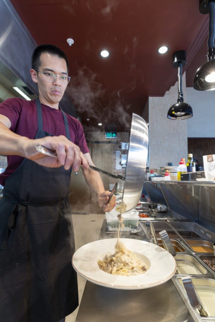 Chef pouring fresh pasta sauce over plated dish at Bianco Italian Restaurant Caloundra