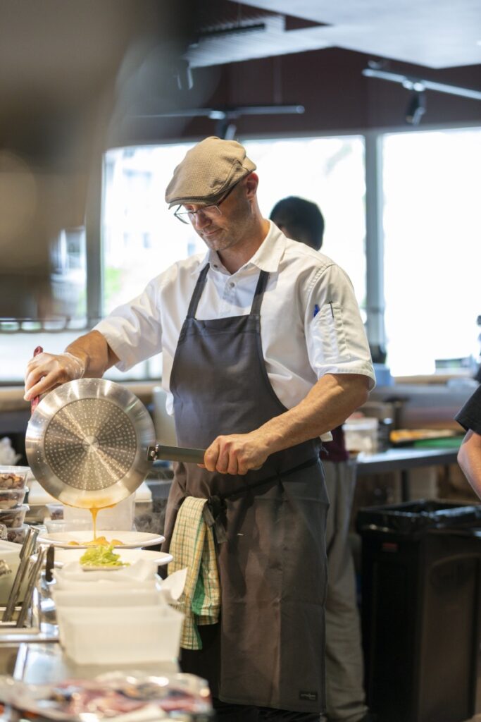 Chef pouring fresh pasta sauce in the kitchen at Bianco Italian Restaurant Caloundra
