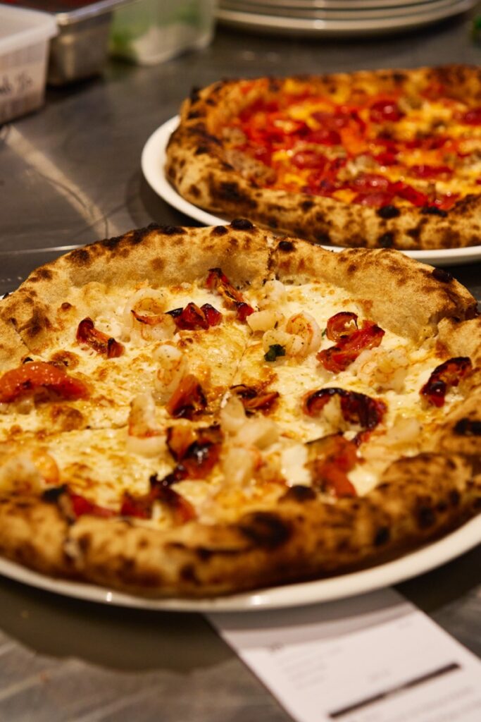Two woodfired pizzas on a stainless steel counter at Bianco Italian restaurant in Caloundra
