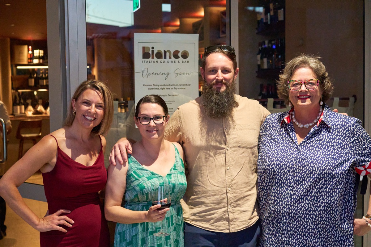 Four guests posing at the Bianco Italian opening night in Caloundra with restaurant signage behind them